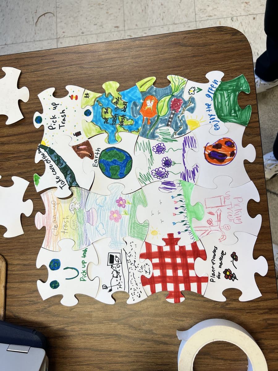 Students coloring puzzle pieces during Earth Day visit